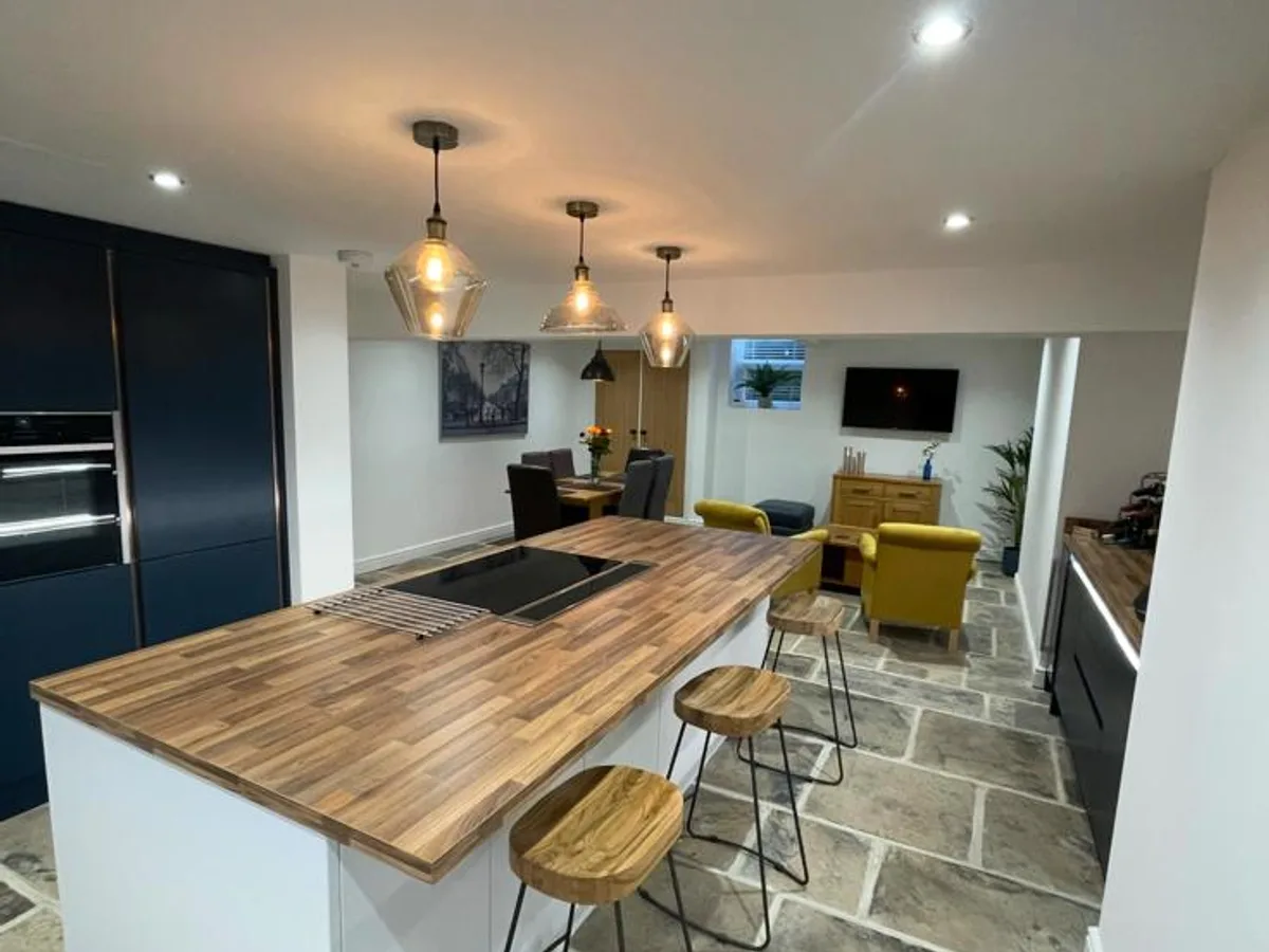 Finished Bingley basement kitchen with timber breakfast bar, pendant lighting and exposed stone wall