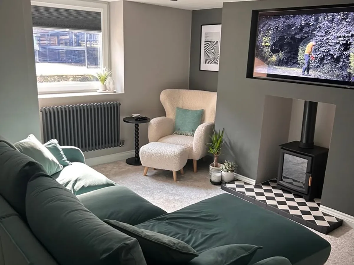 Finished Leeds basement living room with green sofa, log burner and a bright window