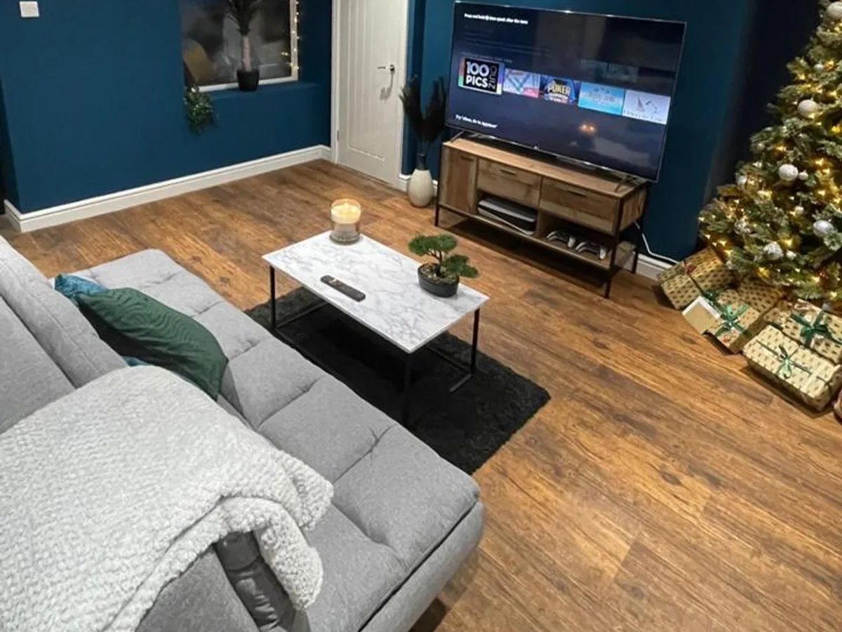 Finished Shipley basement lounge with grey corner sofa, wood-effect flooring and a media wall