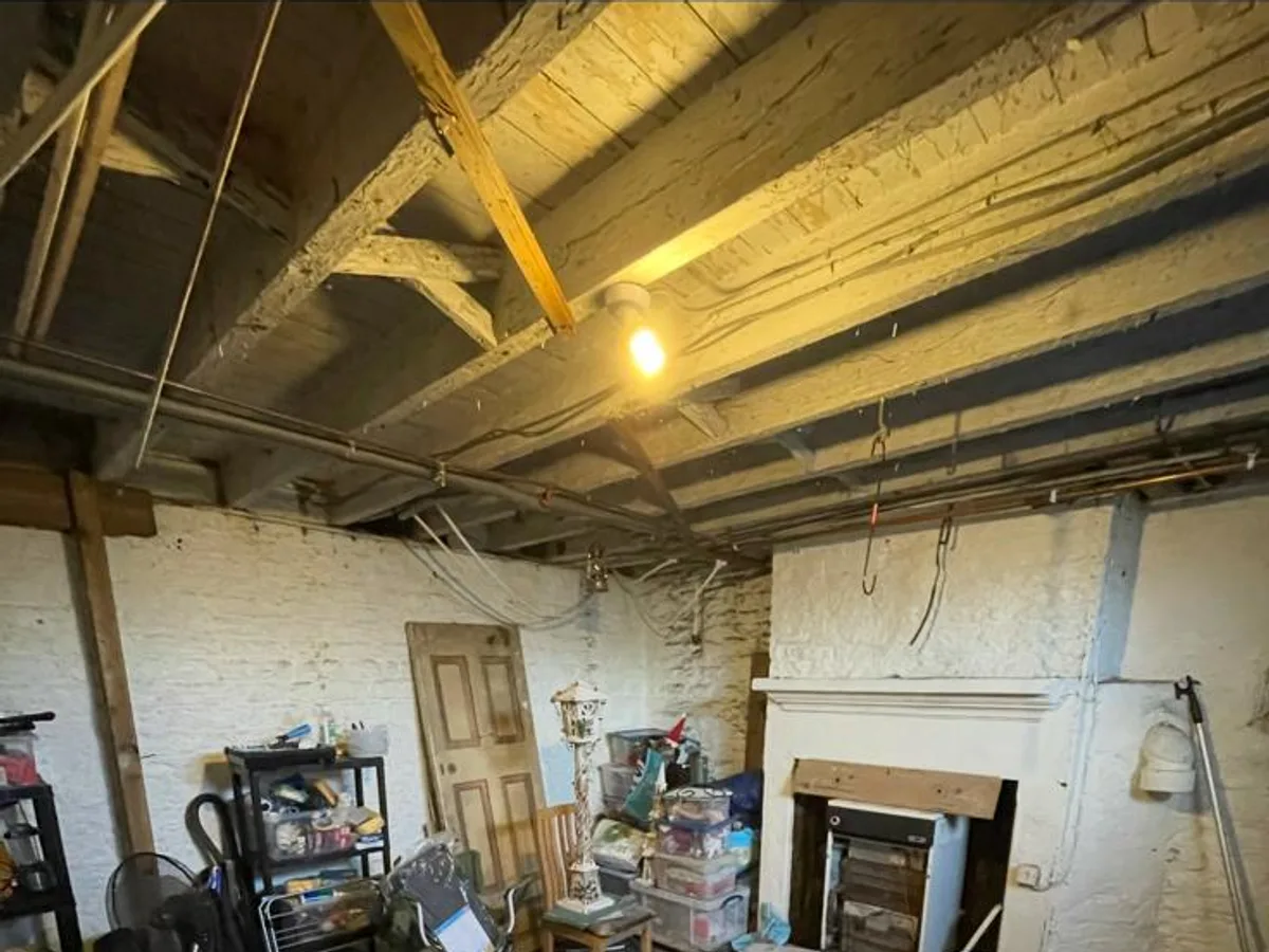 Old Shipley cellar with exposed timber beams, painted brick and stored household items