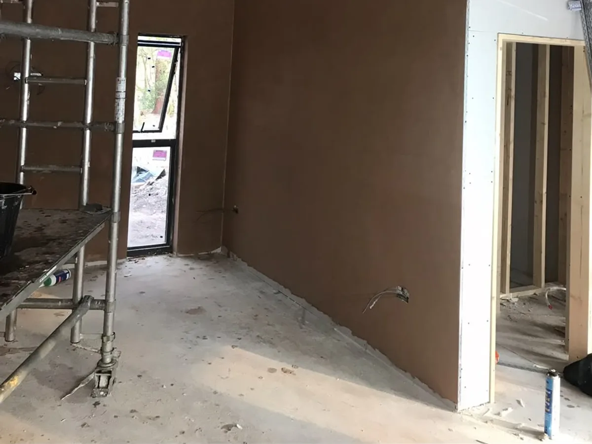 Room freshly plastered by RM Lee, walls flat and paint-ready with the scaffold tower still in place