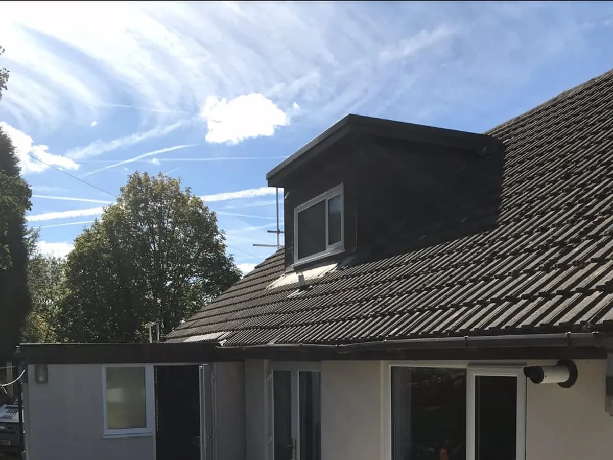 Exterior of a house finished in fresh white render with a tiled roof and dormer